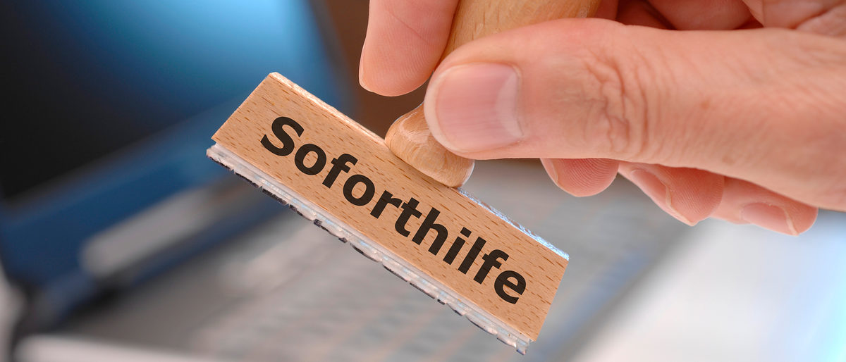 rubber stamp in hand with immediately support (german: Soforthilfe) printed on it