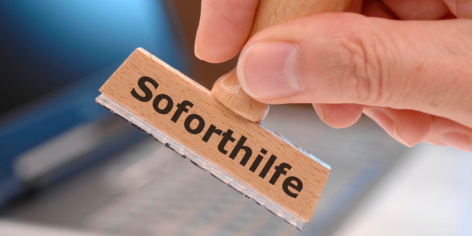rubber stamp in hand with immediately support (german: Soforthilfe) printed on it