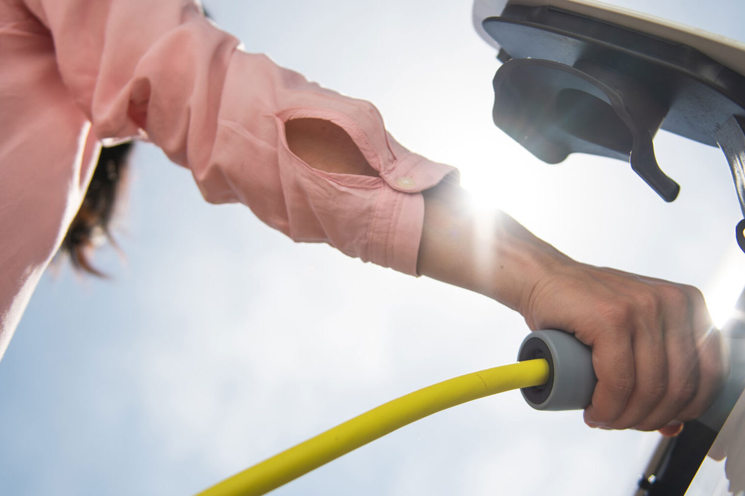 Nahaufnahme, wie jemand ein Elektroauto an eine E-Ladesäule anschließt.