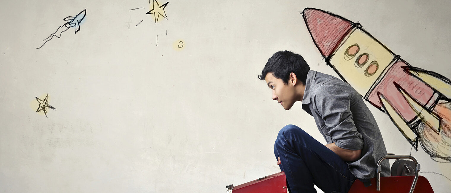 The portrait of a young Asian guy in a red toy car in front of a gray wall with spaceship and planets. Schlagwort(e): Spaceship, Travel, People Traveling, Boys, Men, East Asian Culture, Illustration, Play, Inspiration, Help - Single Word, Driveway, Color Image, Young Adult, Teenager, Playing, Playful, Flying, Leaving, Clambering, Driving, Drawing - Activity, Learning, Backgrounds, Chinese Ethnicity, Asian Ethnicity, Asian and Indian Ethnicities, Caucasian Ethnicity, Business Travel, Motivation, Support, Assistance, Imagination, Beginnings, Dreamlike, Growth, Speed, Concepts, White, Colors, Chinese Culture, Ideas, Business, Outdoors, Surface Level, Occupation, China - East Asia, Star - Space, Moon, Space, Sky, Fire - Natural Phenomenon, Wall - Building Feature, Street, Design, Leisure Games, Rocket, Car, Endorsing, Planetary Moon