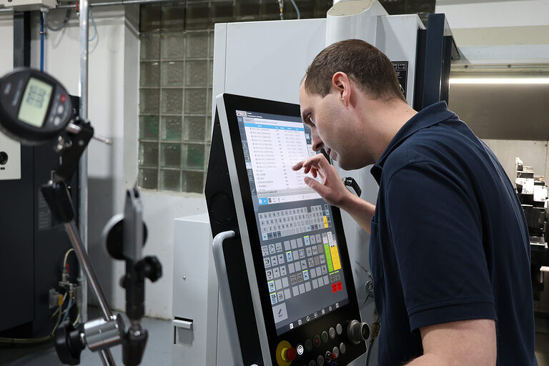 Dominic Haarhoff, Zerspanungsmechaniker mit Sehbehinderung, arbeitet an einer Maschine.