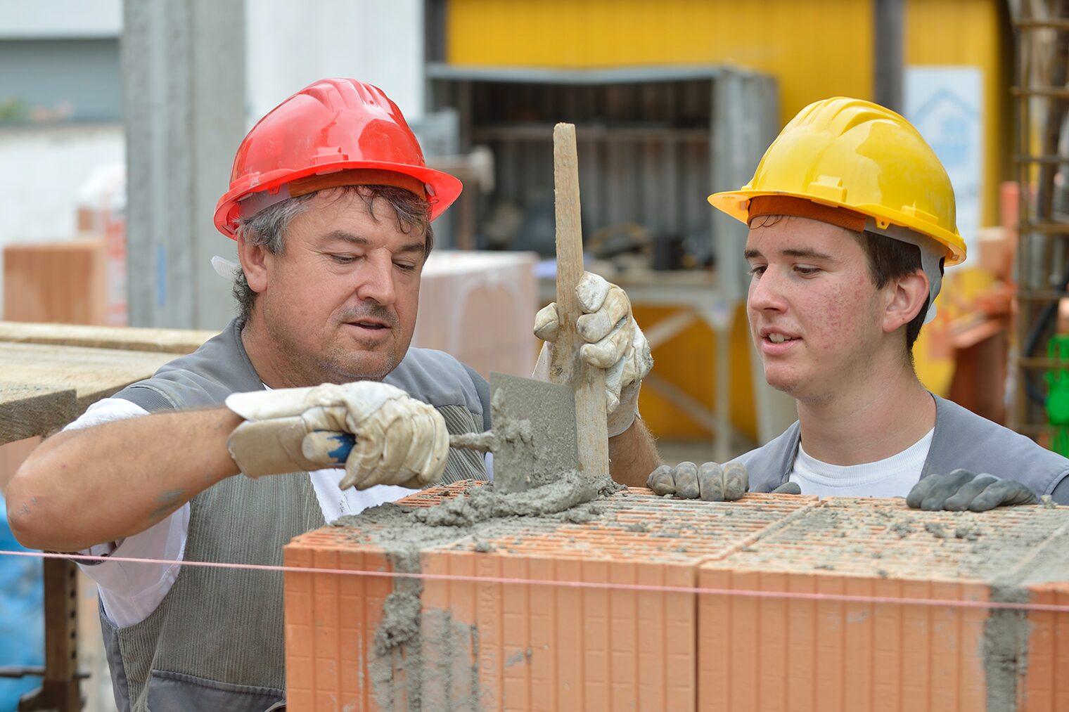 Ein Maurermeister mit einem Praktikanten auf einer Baustelle.