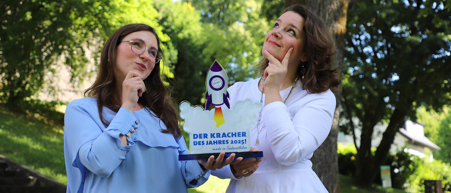 Kracher des Jahres Zwei Frauen halten die Trophäe für den Preis "Kracher des Jahres" in Südwestfalen 2025.
