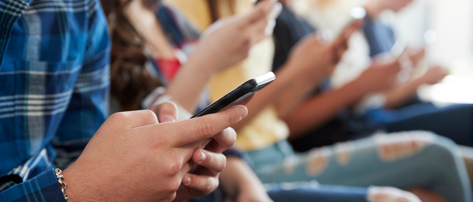 Eine Gruppe Schüler scrollt auf ihren Smartphones.