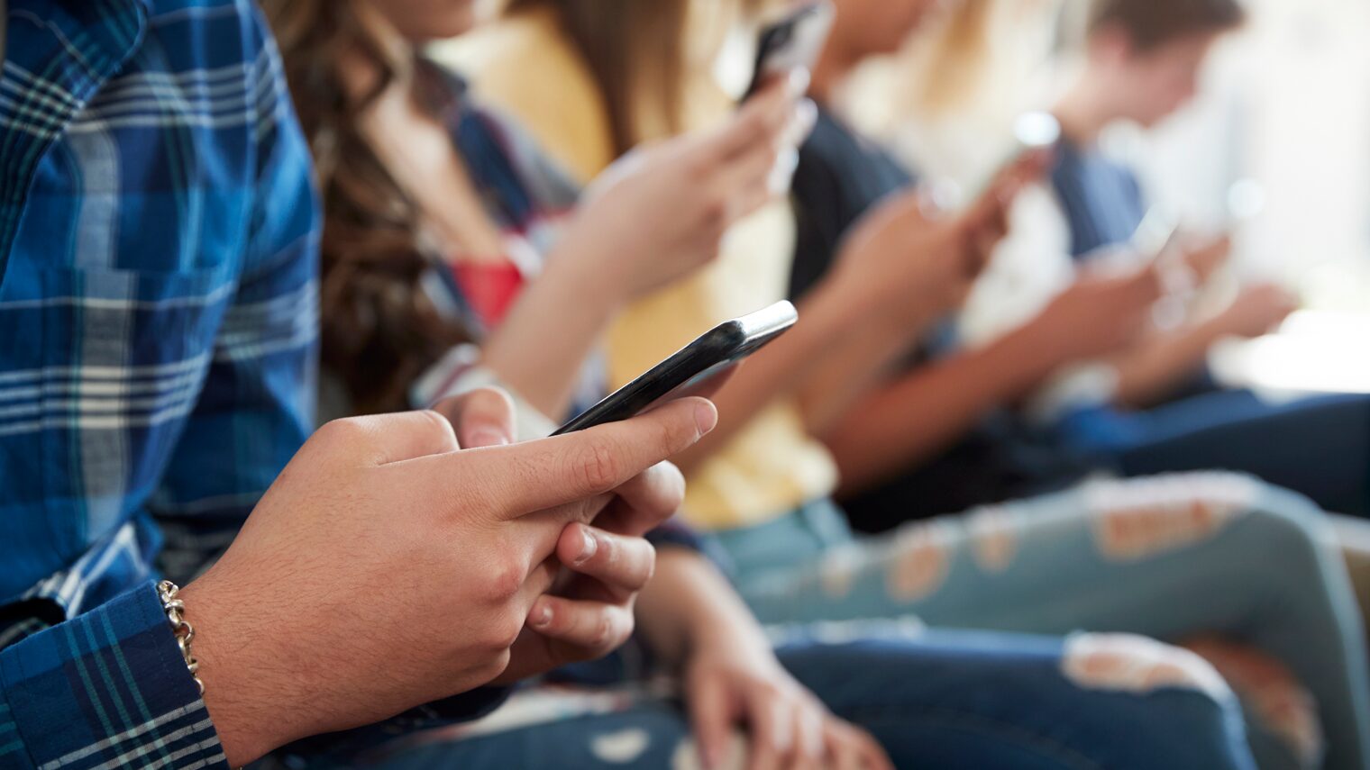 Eine Gruppe Schüler scrollt auf ihren Smartphones.