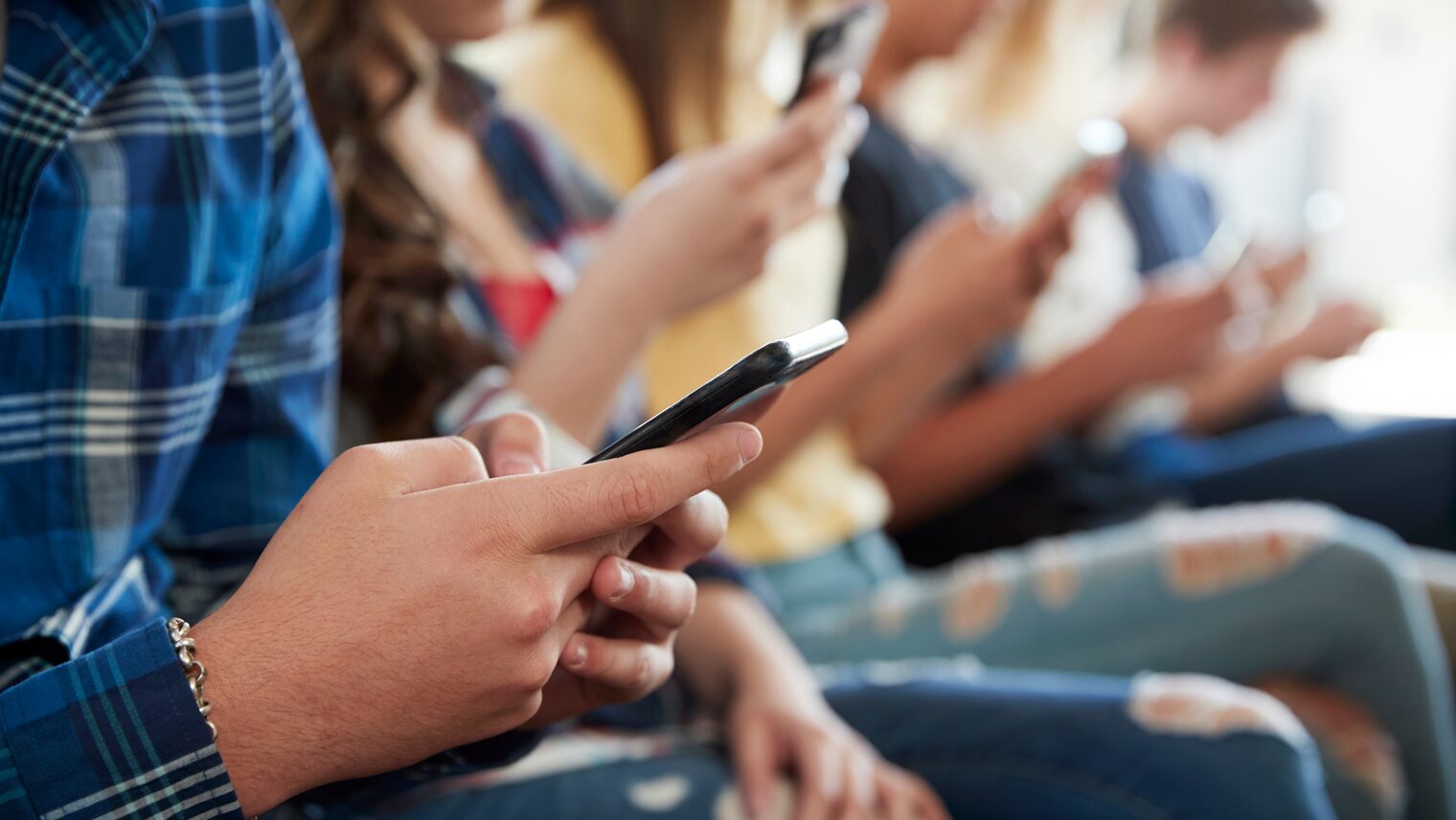 Eine Gruppe Schüler scrollt auf ihren Smartphones.