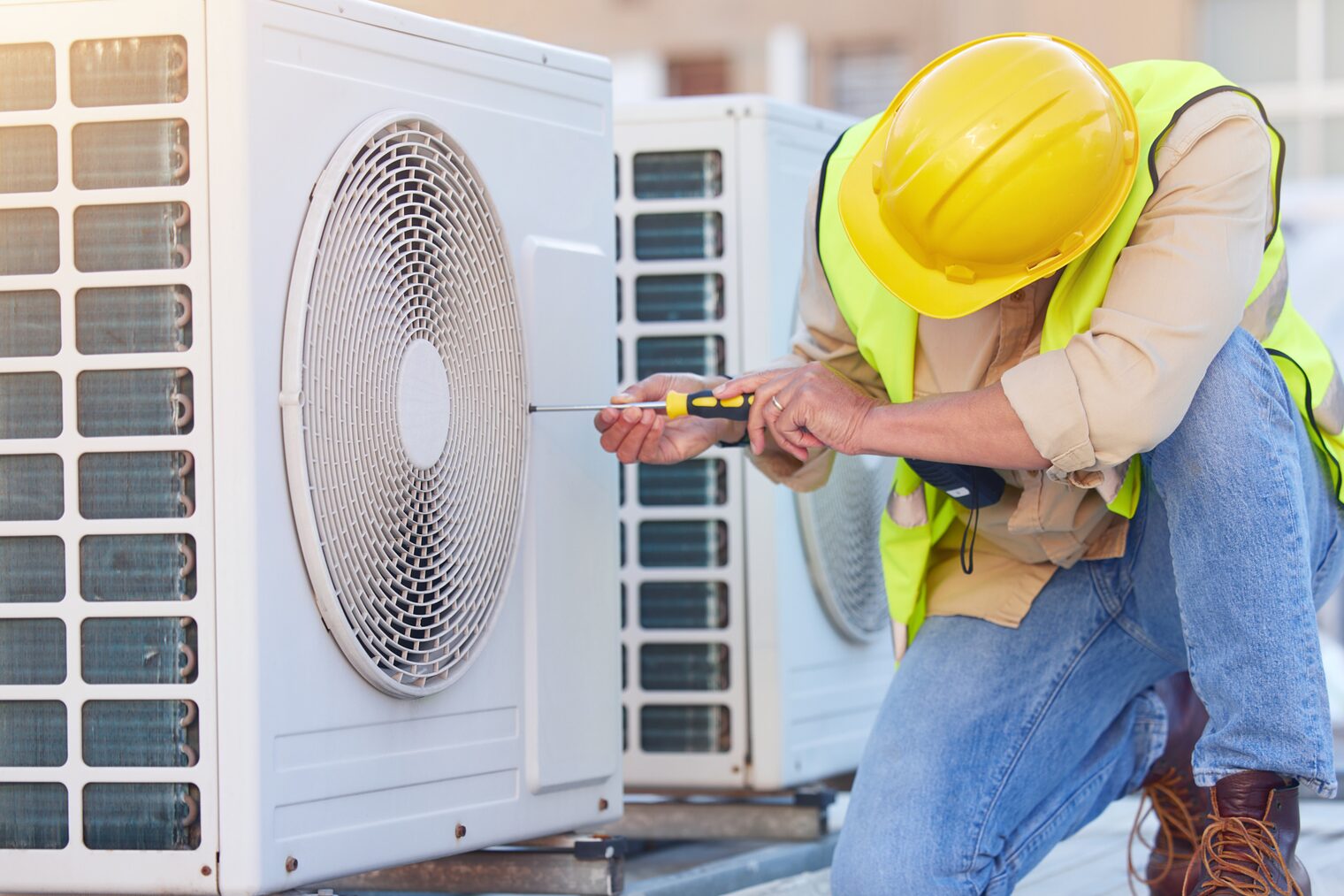 Handwerk und Umweltschutz Ein Handwerker arbeitet an einer Wärmepumpe, die vor einem Gebäude steht.