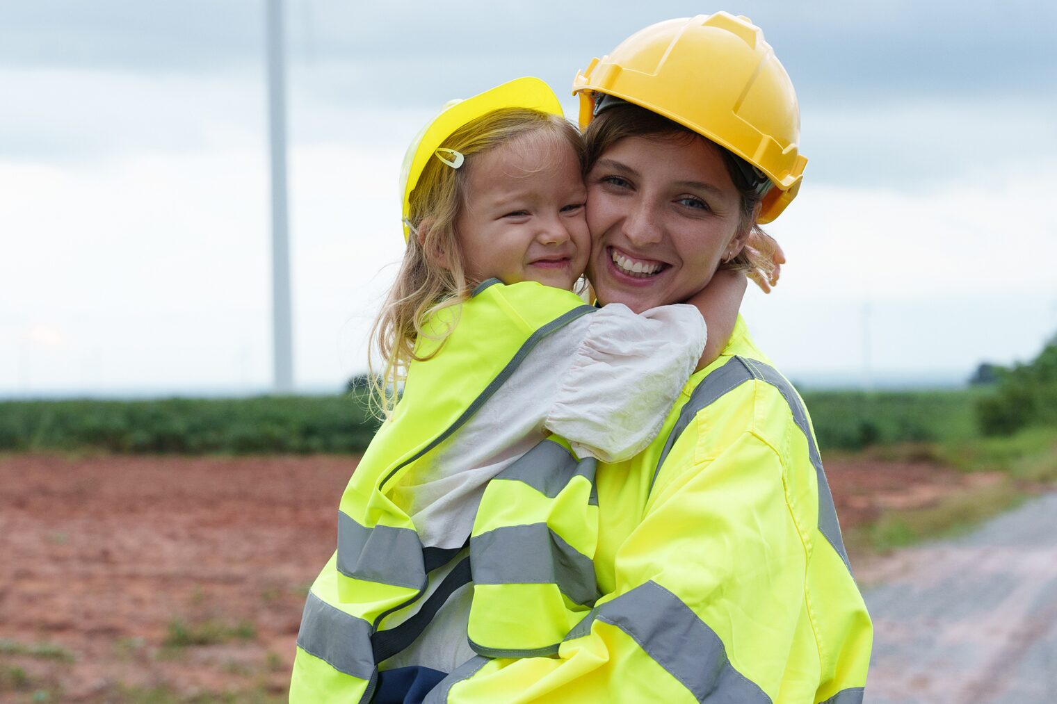 Eine Mutter mit Kind in Warnwesten auf einer Baustelle.