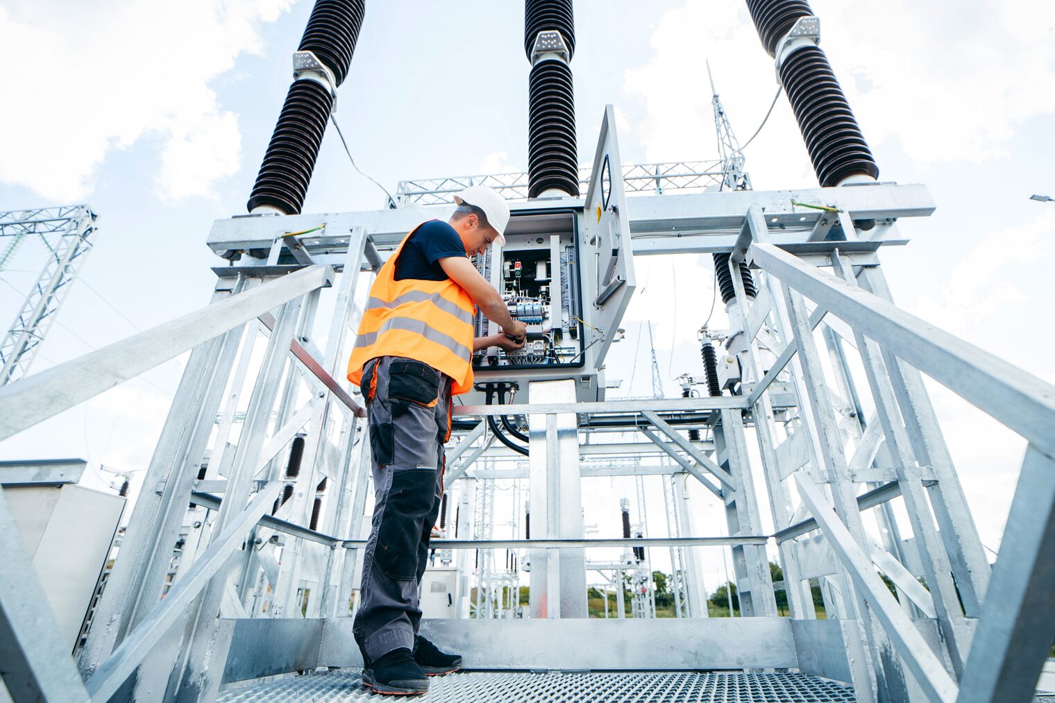 Elektriker am Stromkasten Ein Elektriker arbeitet an einem Stromkasten in einem Umspannwerk.