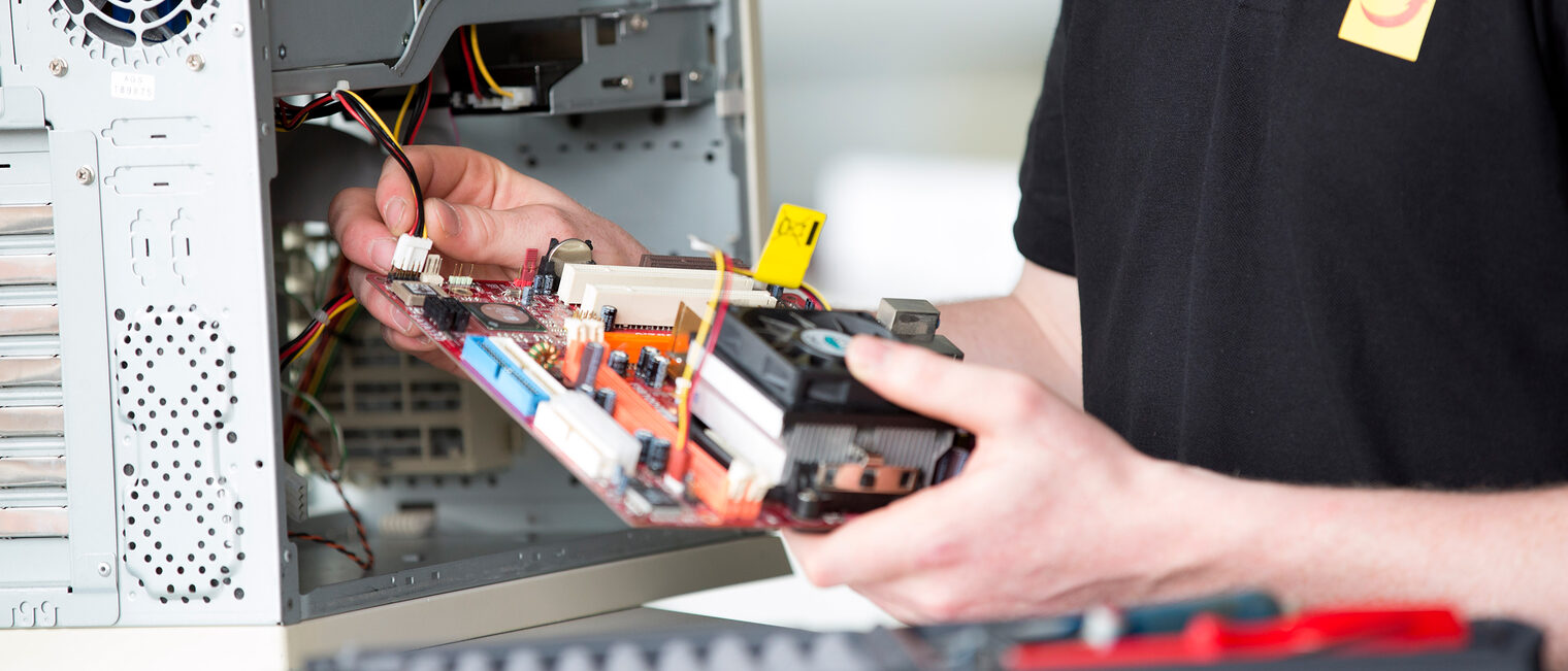 Ein Systemelektroniker arbeitet am Inneren eines Computers.