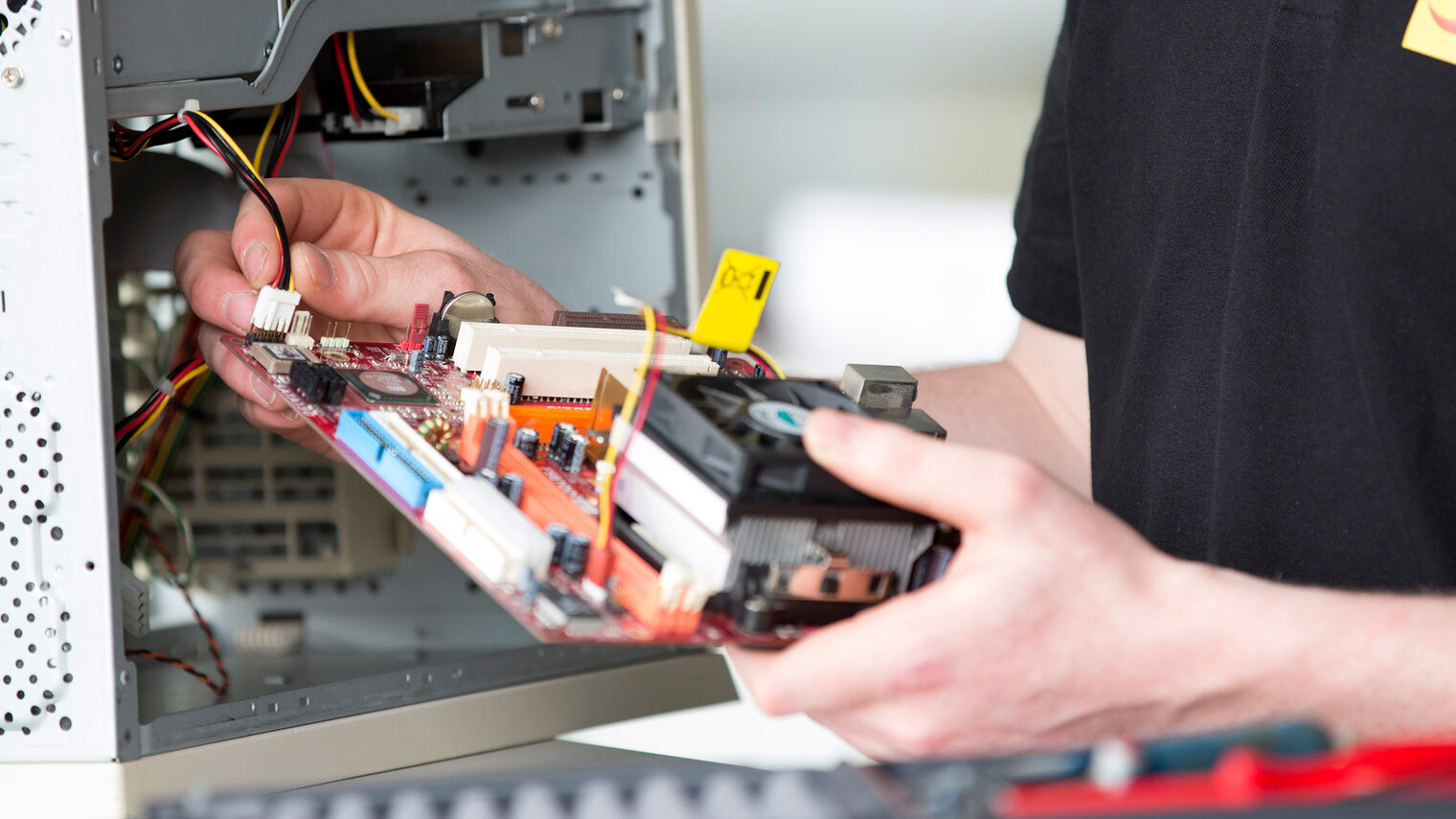 Ein Systemelektroniker arbeitet am Inneren eines Computers.