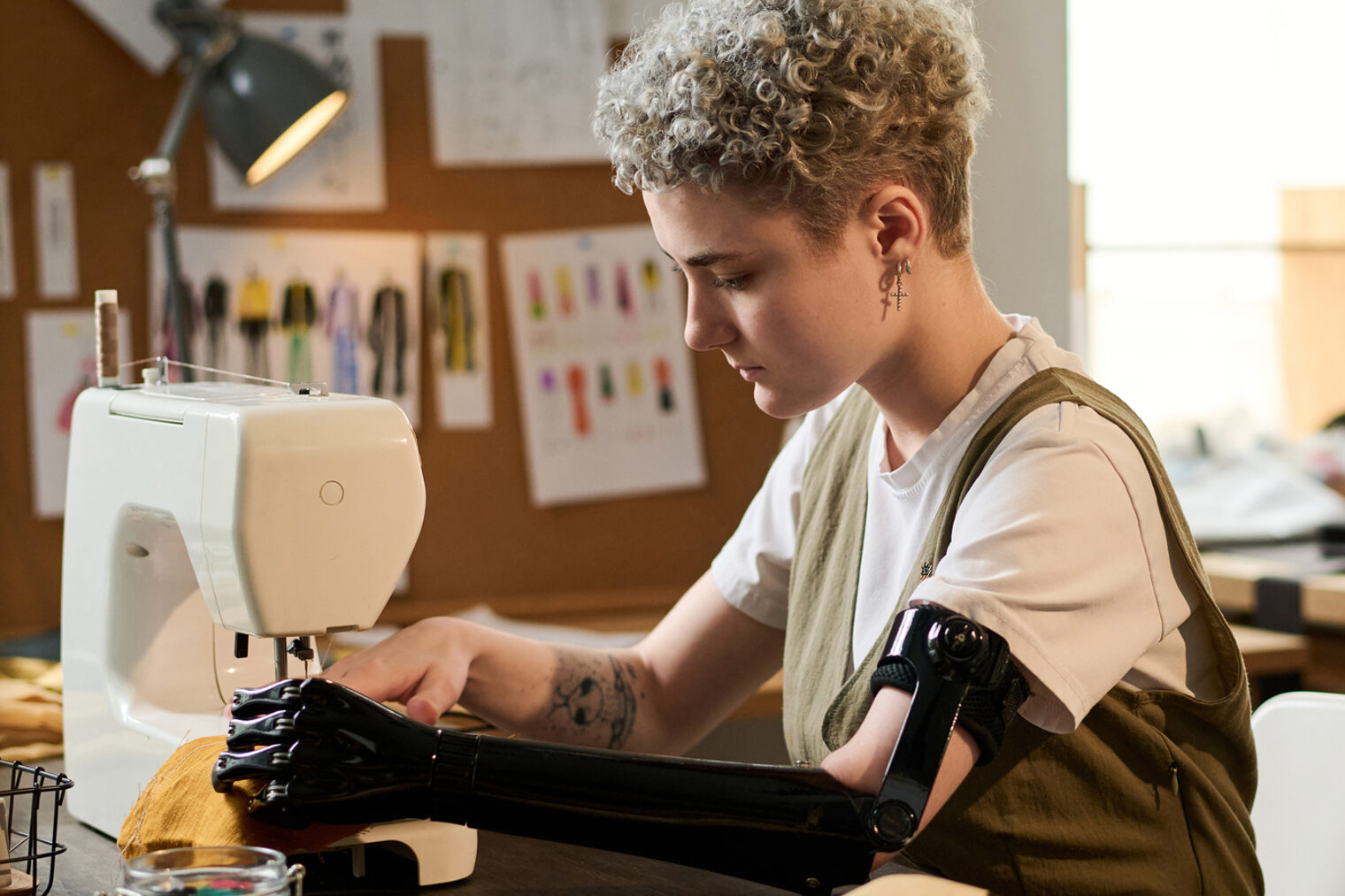 Eine Schneiderin mit Armprothese näht ein Kleidungsstück mit einer Nähmaschine.