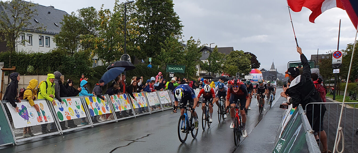 Radrennfahrer sprinten beim Radrennen "Deutschland Tour" auf das Ziel zu. Viele Zuschauer feuern sie am Straßenrand an.