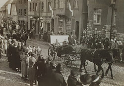 Schwarz-Weiß-Foto vom Umzug zum Reichshandwerkertag Brilon. Zwei Kutschen fahren durch die Stadt, Zuschauer stehen am Rand.