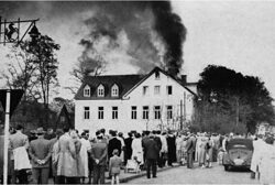 Schwarz-Weiß-Foto von Schaulustigen, die den Dachstuhlbrand an der Verwaltung der Handwerkskammer Arnsberg 1955 beobachten.
