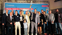 Ein Gruppenfoto von der Siegerehrung des Ausbildungspreises 2024. Die Gewinner halten Trophäen in die Höhe.