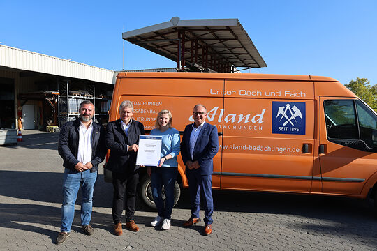Gruppenfoto mit Vertretern der Handwerkskammer, Signal Iduna und von Aland Bedachungen. Im Hintergrund ist das Firmengelände.
