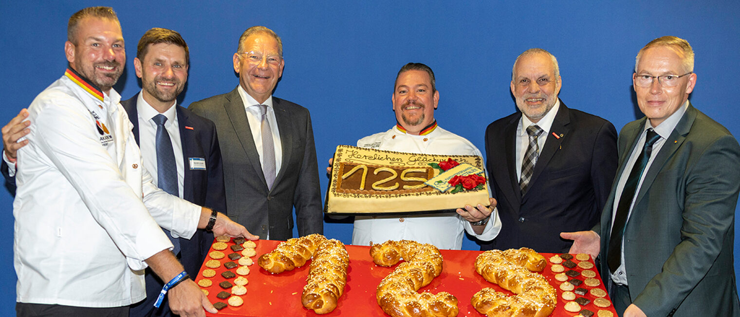 Vertreter der Bäckerfachschule Olpe überreichen zu "125 Jahre Handwerkskammer Südwestfalen" einen Hefezopf und eine Torte.
