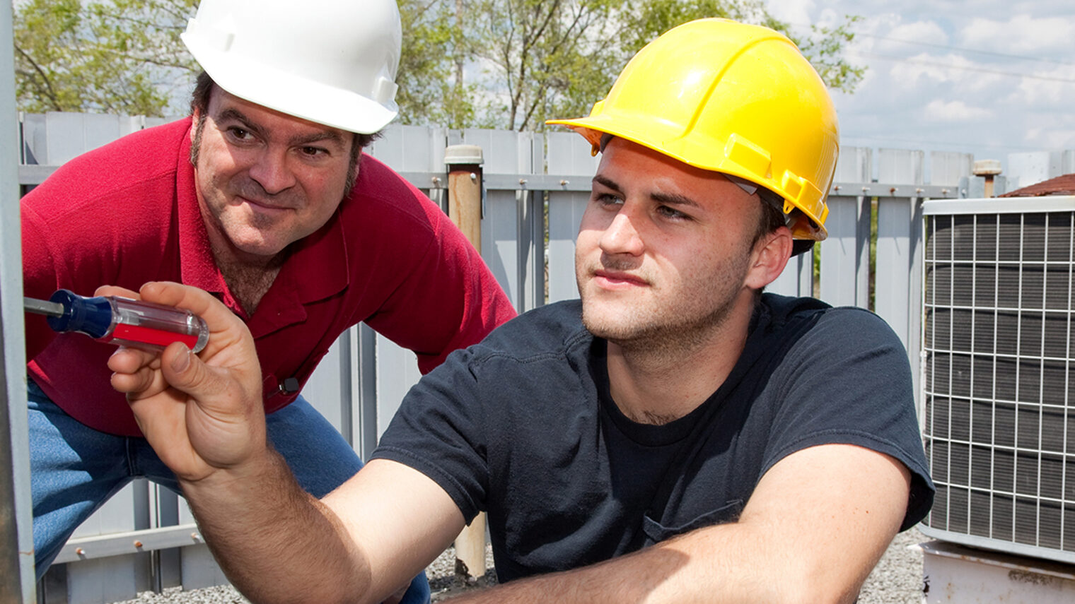 Air conditioning repair apprentice fixes an industrial compressor unit as his supervisor watches. Schlagwort(e): Alternating Current