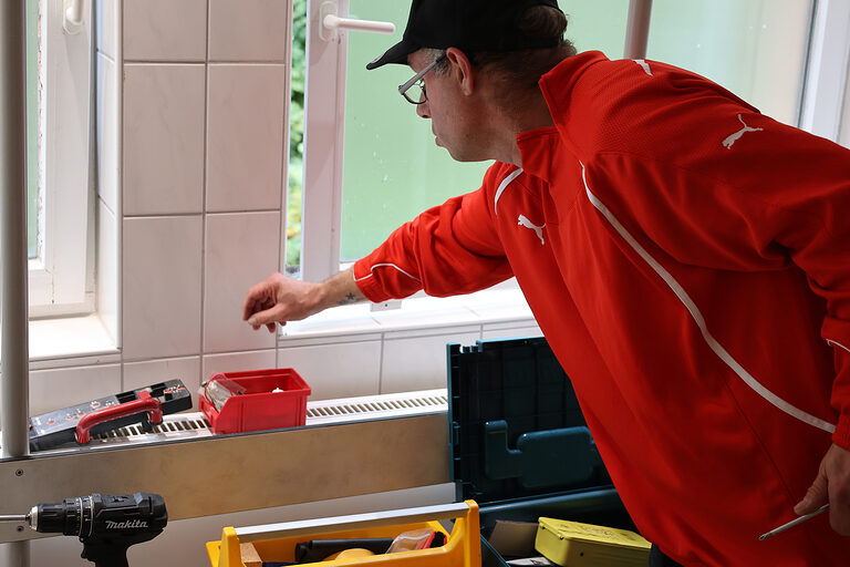 Gregor Hesse greift nach Werkzeug, das auf einem Tisch abgelegt wurde.