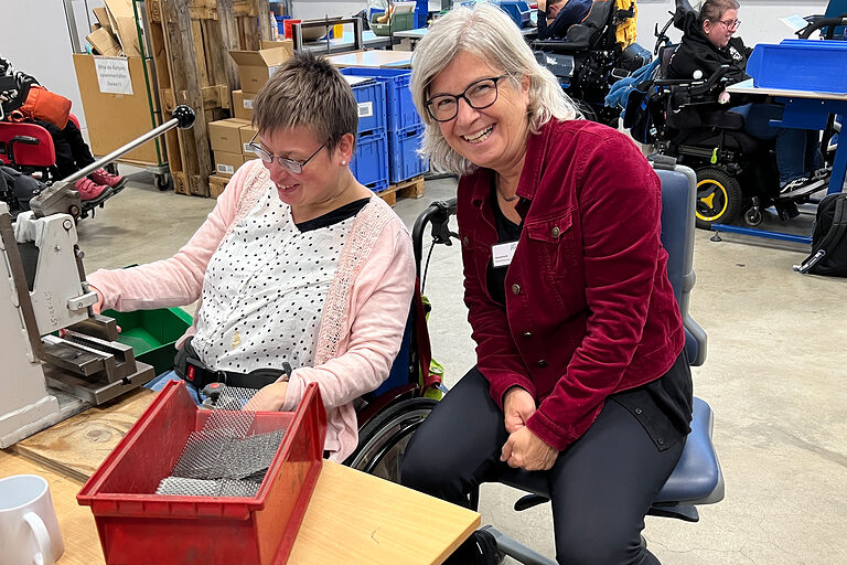 Verena Kurth zusammen mit einer Mitarbeiterin der Werkstätten des Bigger Josefsheim an einer Maschine.