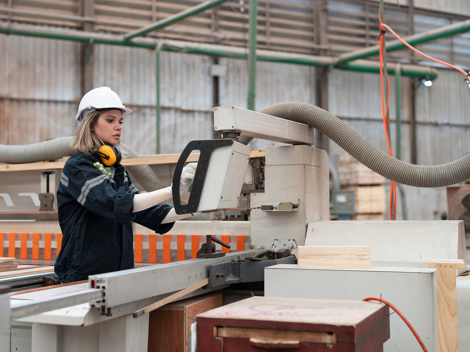 Eine Tischlerin arbeitet an einer modernen CNC-Maschine in einer Werkstatt.