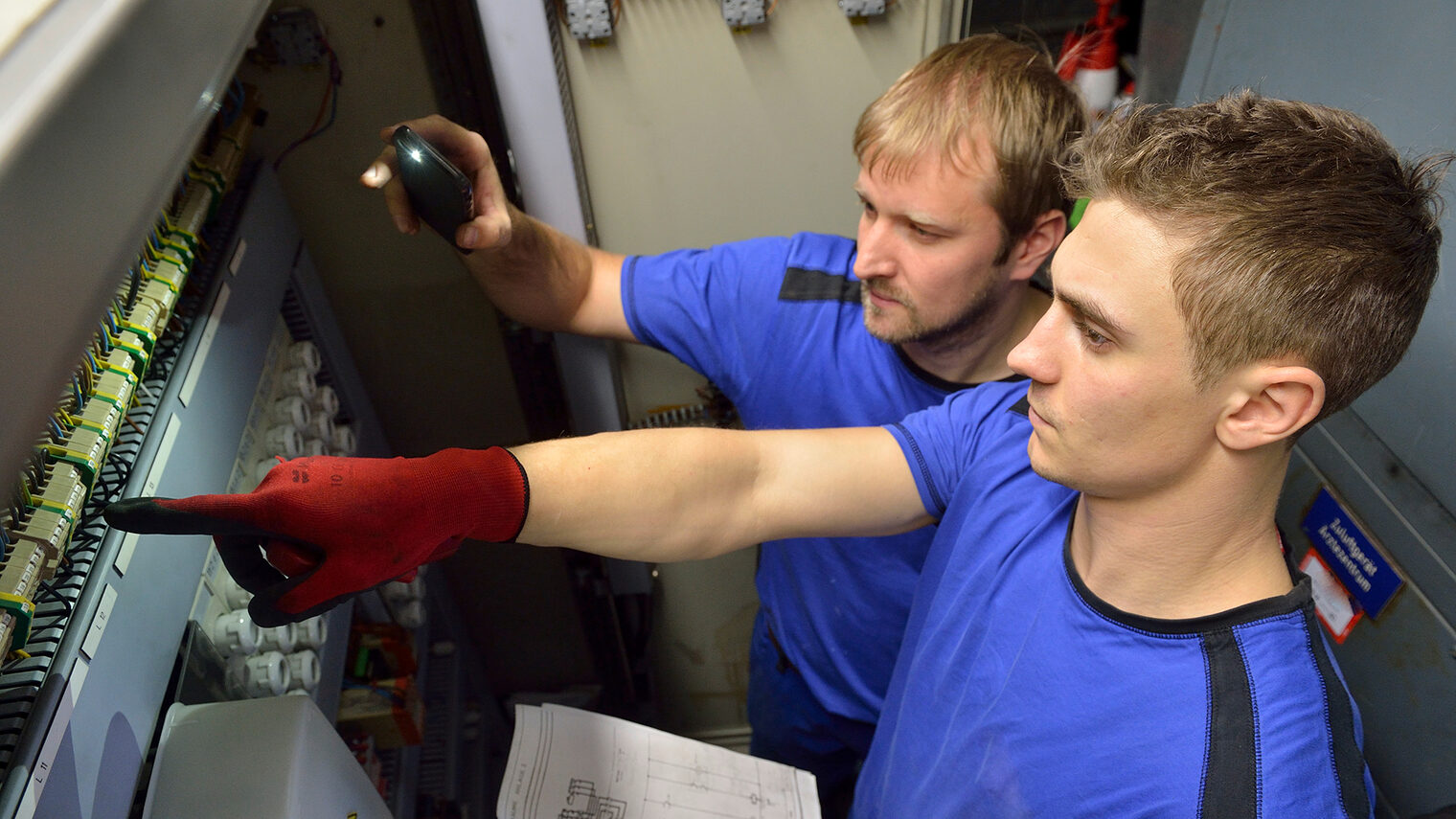 Ein Auszubildender für den Beruf Mechatroniker für Kältetechnik zusammen mit seinem Ausbilder bei der Arbeit.