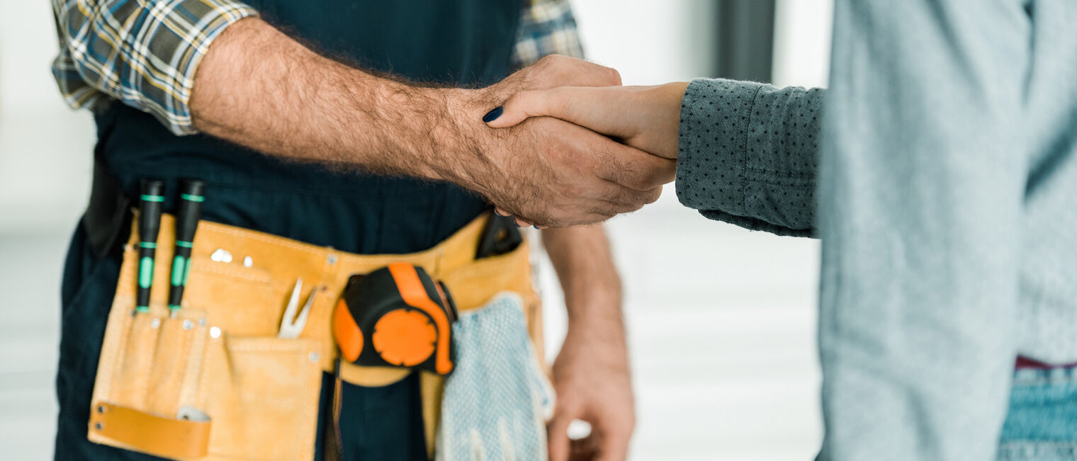 Handwerk Ein Handwerker und eine weitere Person begrüßen sich per Handschlag.