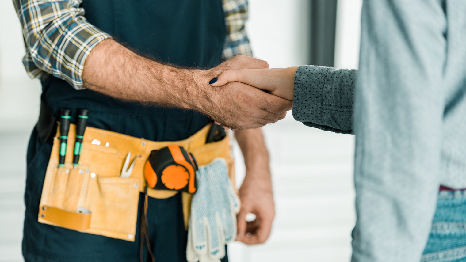 Ein Handwerker und eine weitere Person begrüßen sich per Handschlag.