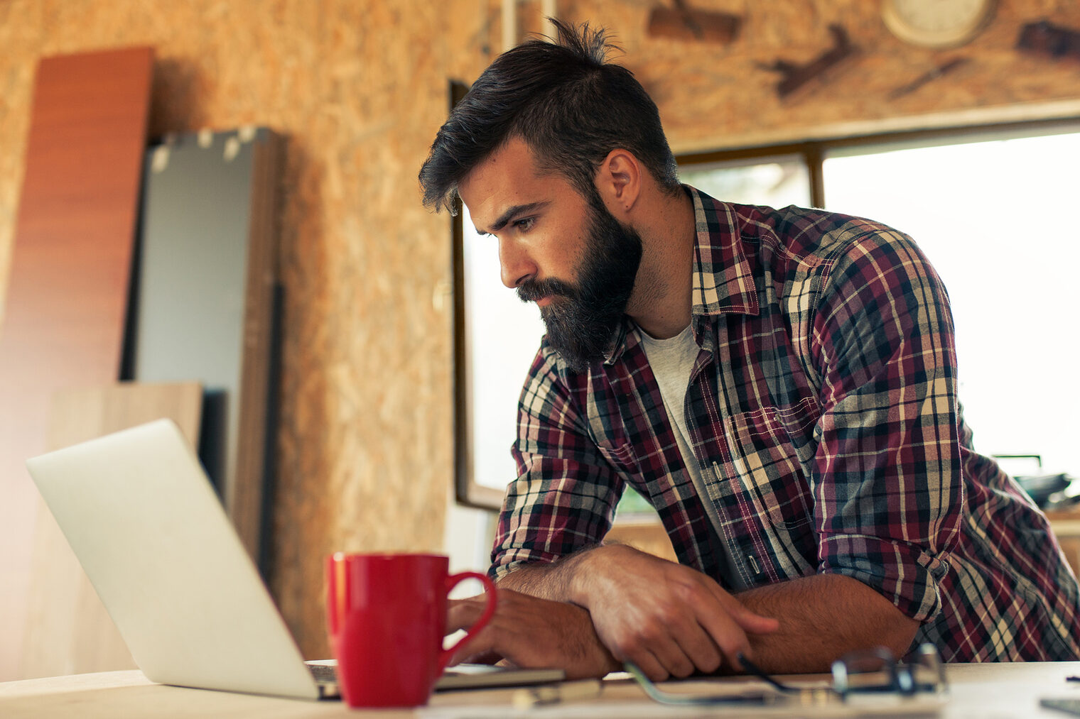 Ein Tischler arbeitet an einem Laptop in seiner Werkstatt.