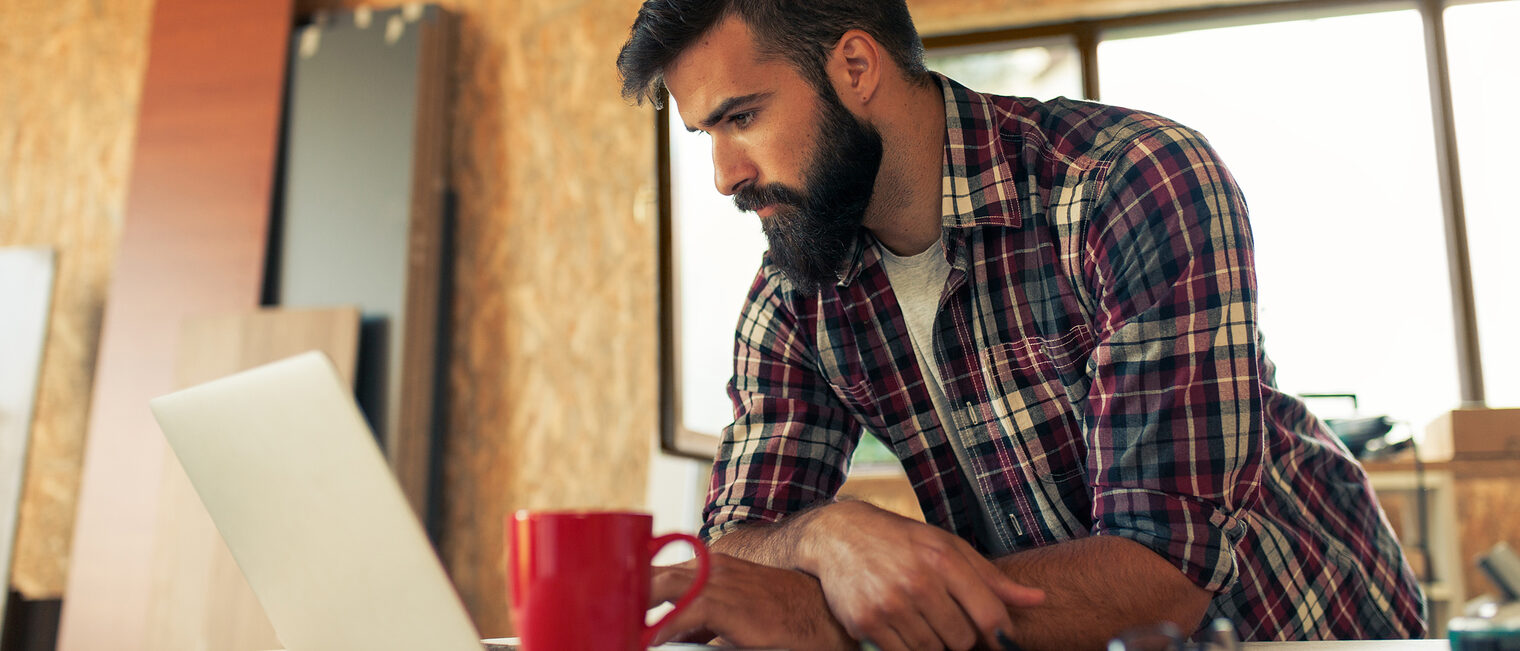 Handwerker mit Laptop Ein Tischler arbeitet an einem Laptop in seiner Werkstatt.