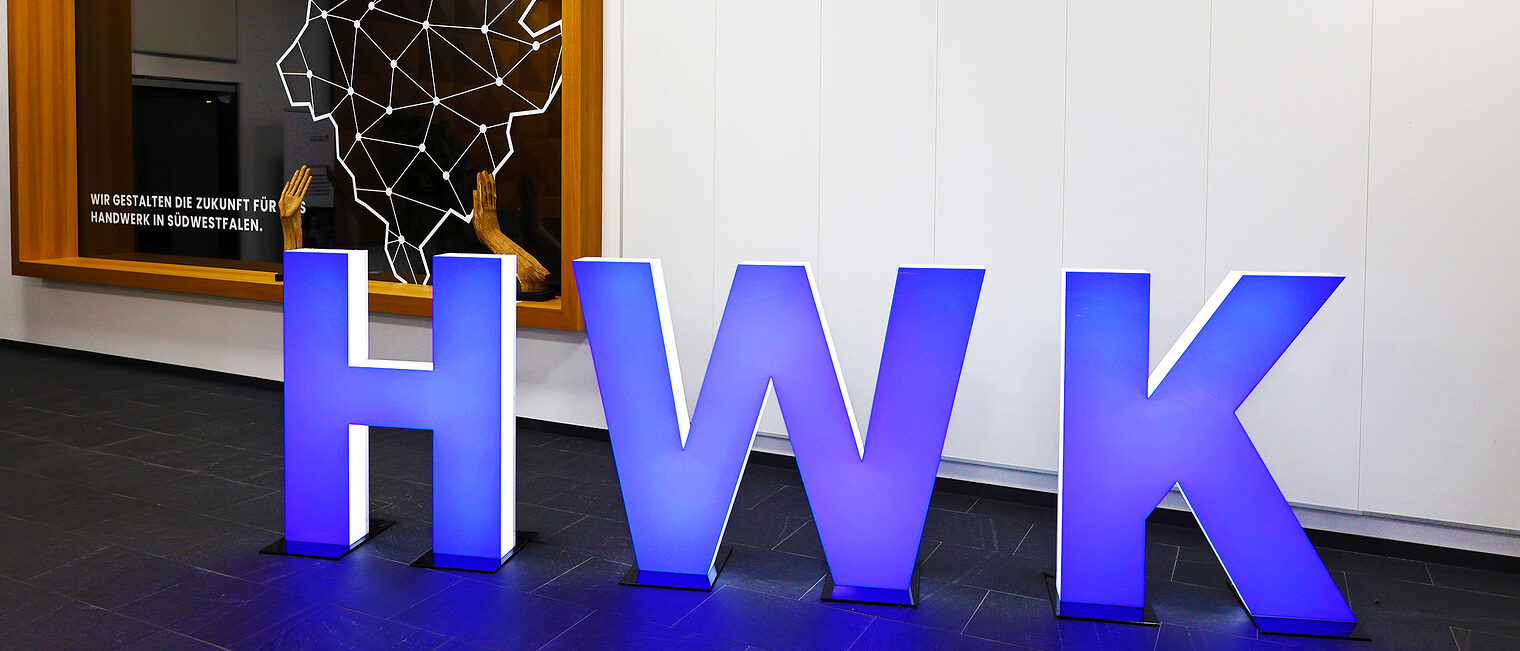 HWK Skulpturen der Buchstaben HWK (Abkürzung für Handwerkskammer) stehen blau leuchtend im Foyer der Handwerkskammer Südwestfalen
