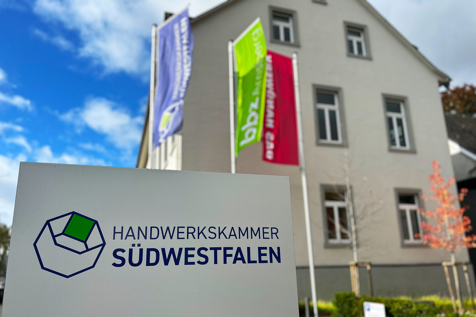 Schild mit dem Logo und der Aufschrift "Handwerkskammer Südwestfalen" vor dem Eingang zum Verwaltungsgebäude der Kammer.