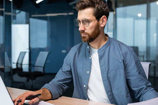 Mann arbeitet an einem Laptop. 