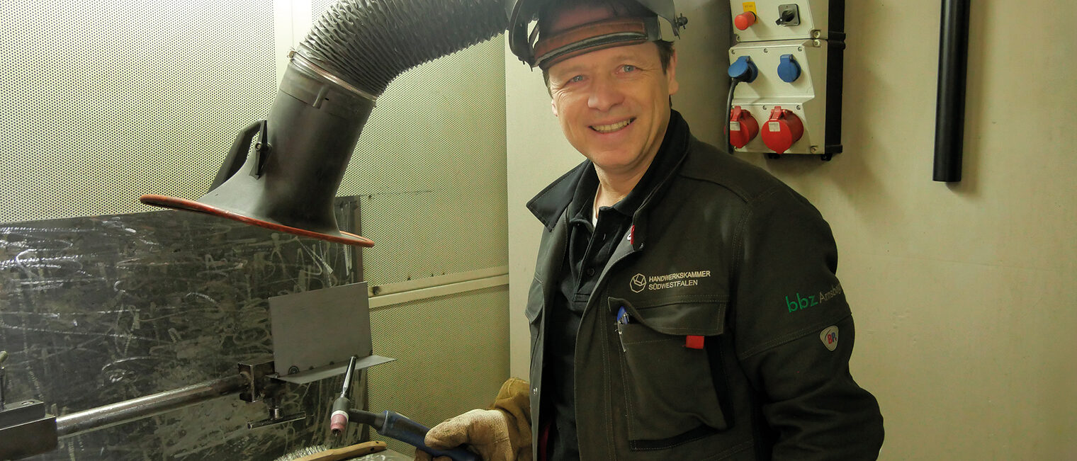 DVS-Schweißlehrer in Arbeitskleidung in einer Werkstatt im Berufsbildungszentrum Arnsberg.