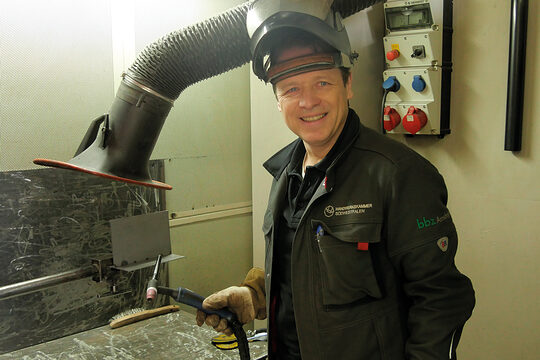 DVS-Schweißlehrer in Arbeitskleidung in einer Werkstatt im Berufsbildungszentrum Arnsberg.