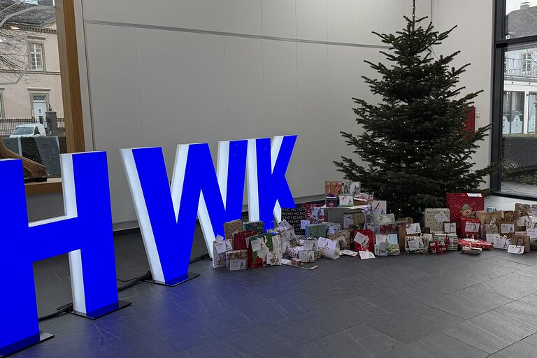 Gepackte Geschenke liegen rund um einen Weihnachtsbaum im Foyer der Handwerkskammer Südwestfalen.