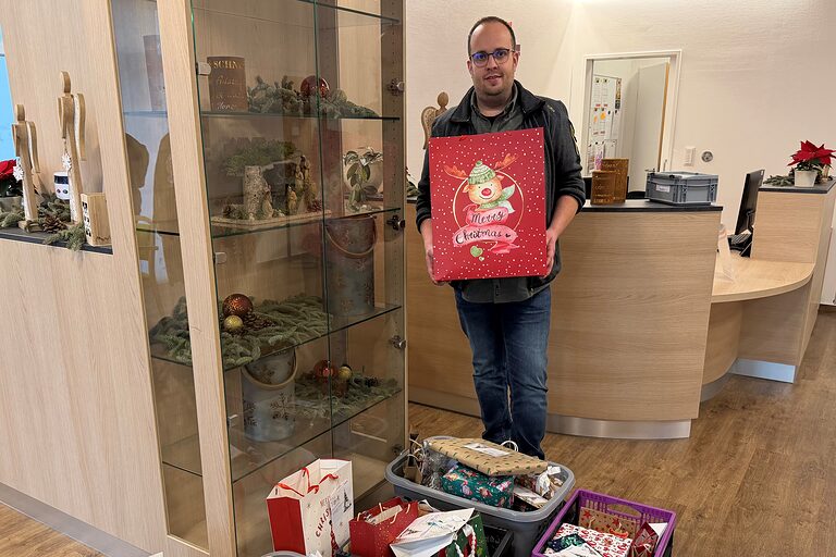 Ein Mann nimmt Geschenke im Eingangsbereich eines Seniorenheims entgegen.