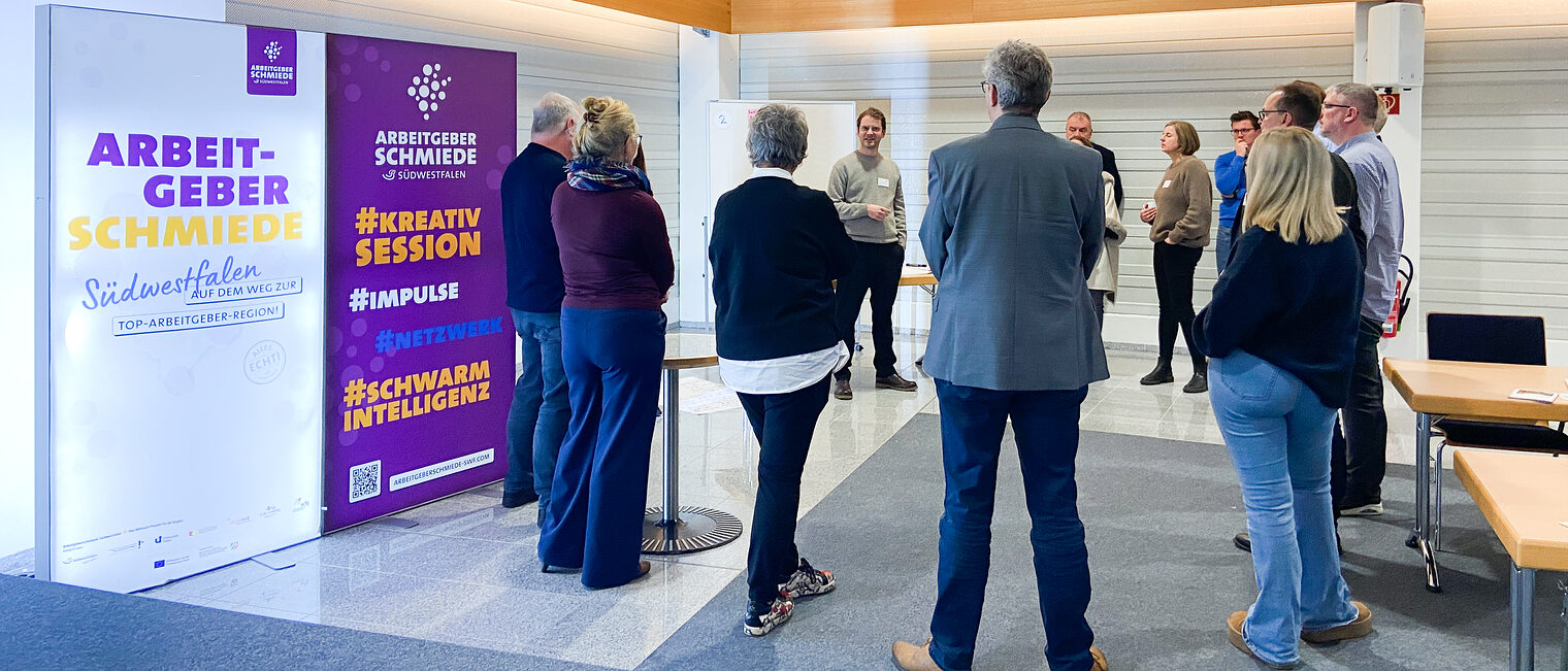 Eine Gruppe Menschen steht im Kreis und hört einen Vortrag bei der Arbeitgeberschmiede Südwestfalen