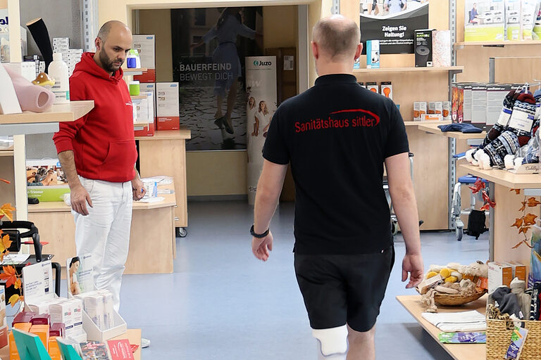 Orthopädietechniker Tojiddin Rahmov schaut einem Kunden zu, der eine Unterschenkelprothese testet.