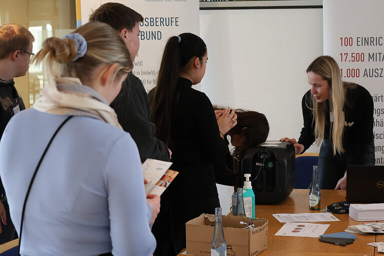 Schülerinnen und Schüler führen praktische Übungen an einem Berufsinfostand der GFO Kliniken Südwestfalen durch.