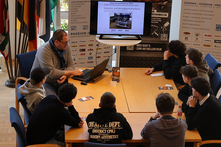 Schülerinnen und Schüler verfolgen eine Präsentation eines Fahrzeugbaubetriebes.