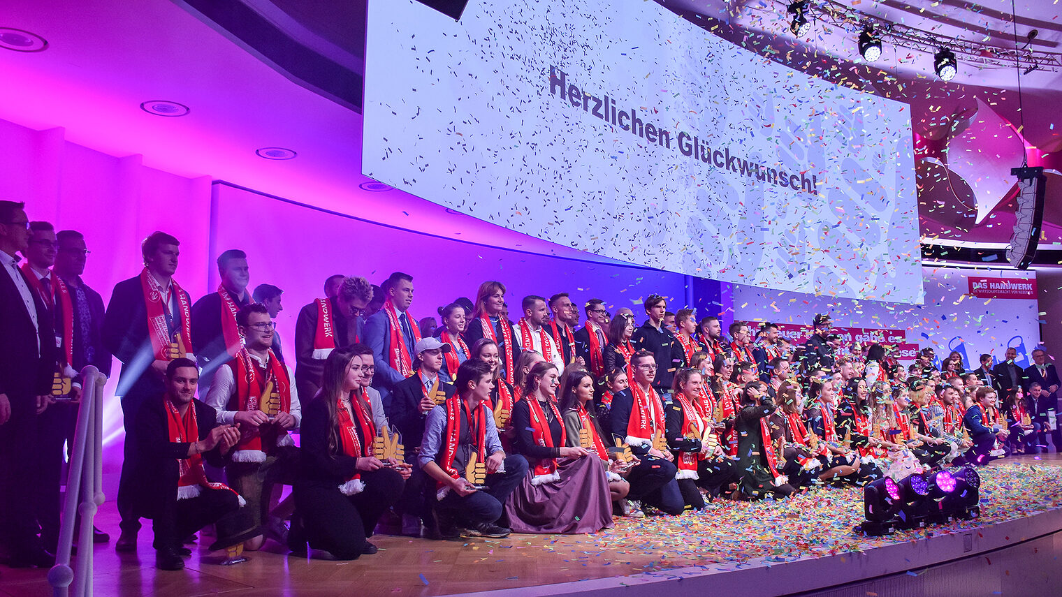 Gruppenfoto der Preisträgerinnen und Preisträger des Wettbewerbs "Die gute Form" im Jahr 2023 auf einer Bühne in Berlin.