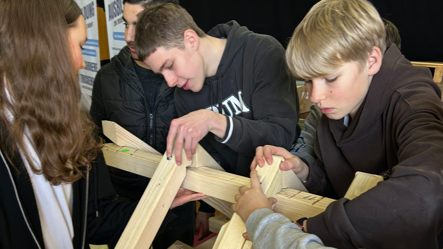 Zwei Jungs und ein Mädchen arbeiten mit Holzbalken.