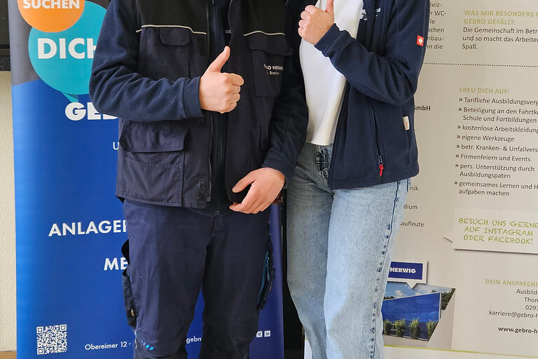 Ein junger Mann und eine junge Frau vor Werbeaufstellern des Betriebs GEBRO HERWIG Haustechnik GmbH.