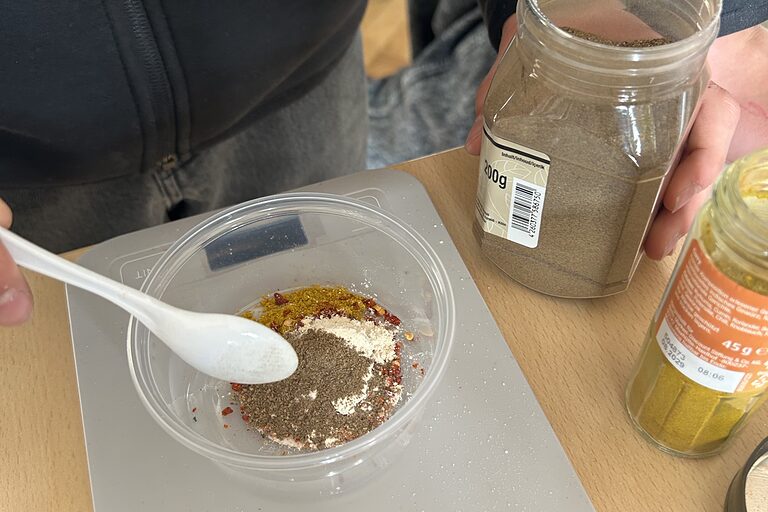 Ein Schüler rührt verschiedene Gewürze in einer Schüssel zusammen.