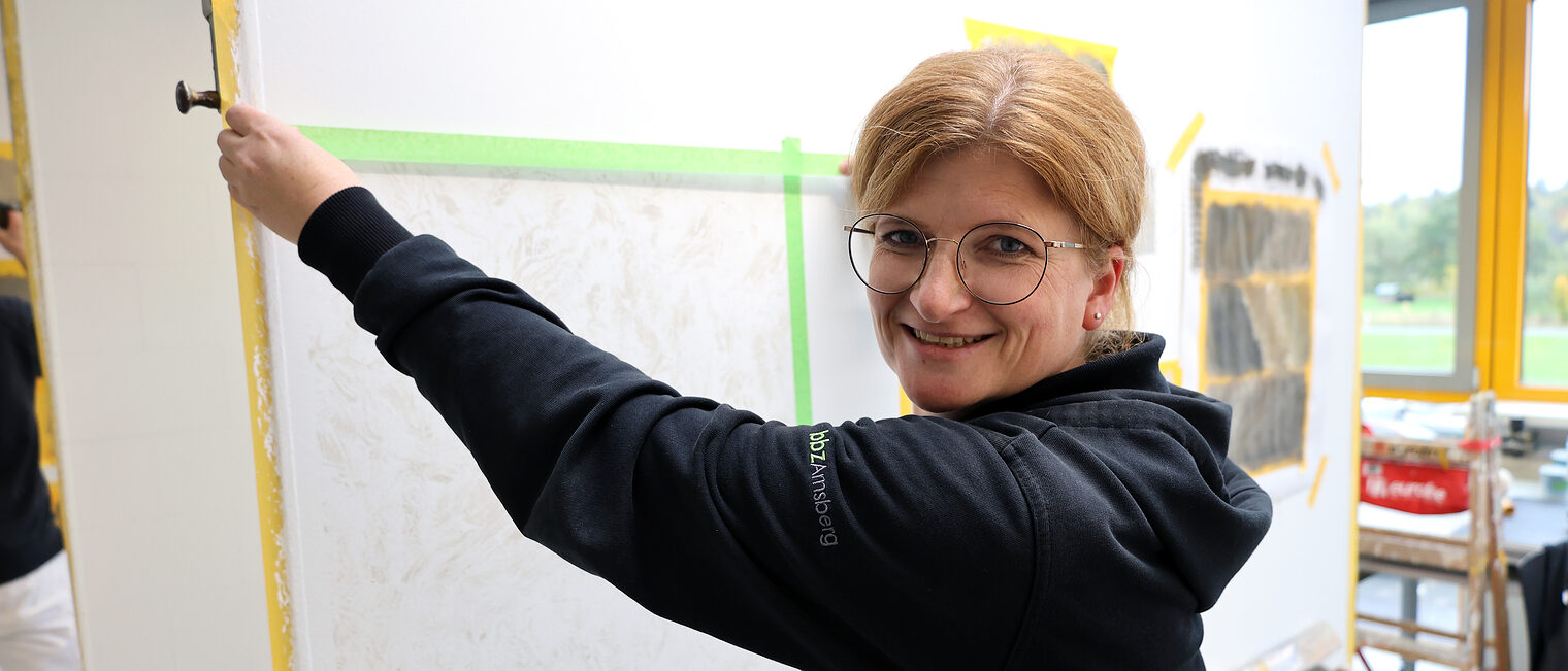 Eine Frau in einer Malerwerkstatt, die eine Fläche abklebt.