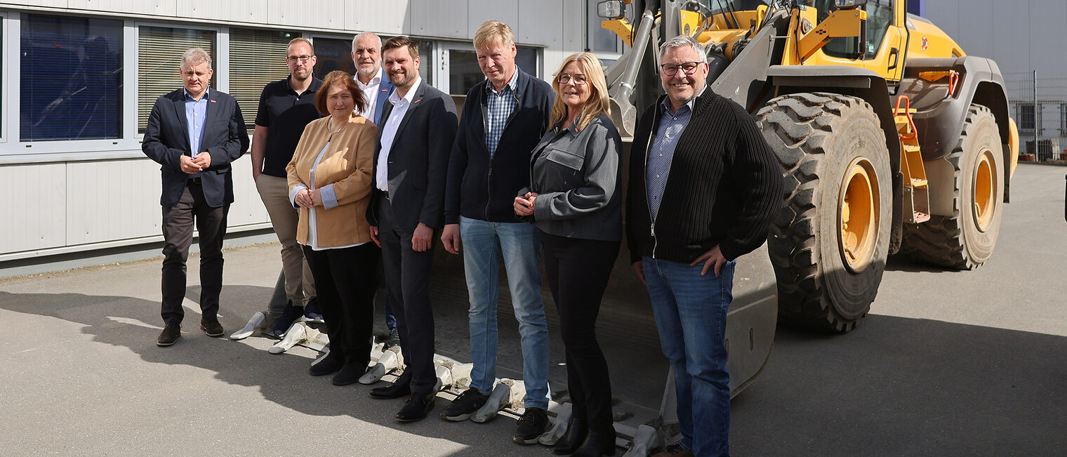 Gruppenfoto mit Bettina Lugk sowie Betriebsvertretern und Vertretern der Handwerkskammer. Im Hintergrund steht ein Bagger.