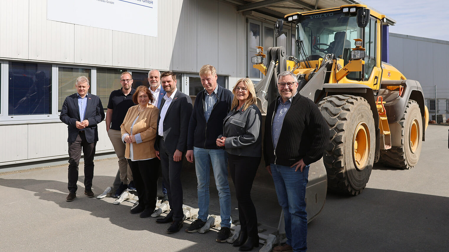 Gruppenfoto mit Bettina Lugk sowie Betriebsvertretern und Vertretern der Handwerkskammer. Im Hintergrund steht ein Bagger.