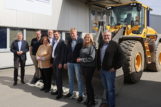 Gruppenfoto mit Bettina Lugk sowie Betriebsvertretern und Vertretern der Handwerkskammer. Im Hintergrund steht ein Bagger.